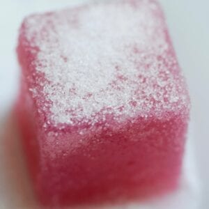 Pink sour grape gummy with a sweetener dusting