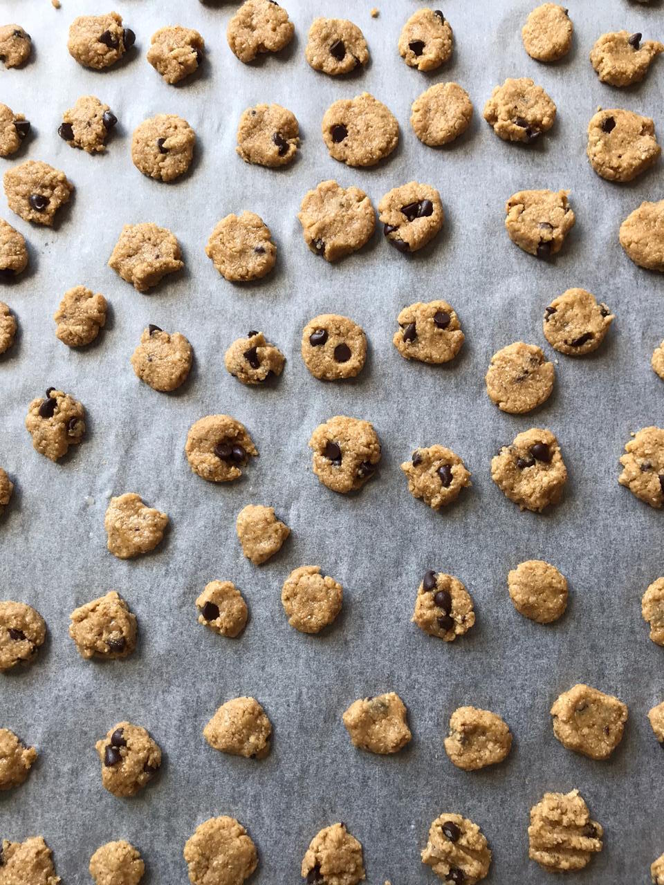 Rolling mini cookie dough balls onto a baking tray