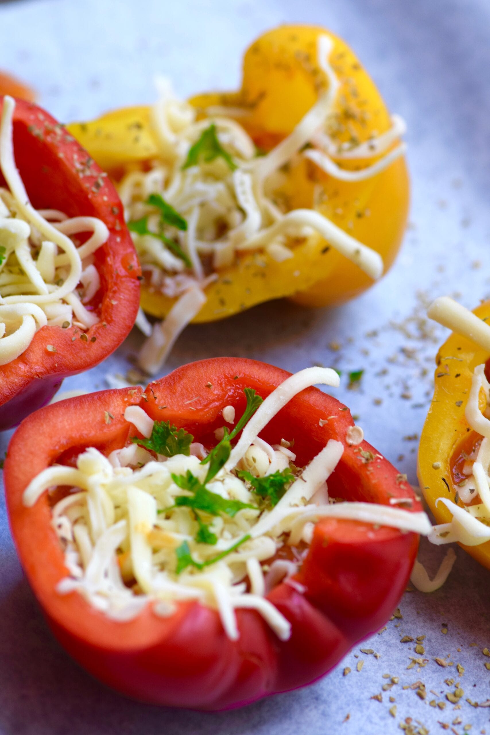 Adding cheese, tomato and spices to the bell peppers