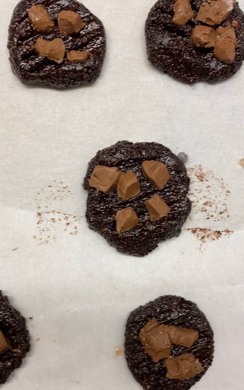 Rolling raw cookie dough for the fudgy chocolate brownie cookies onto a sheet of baking paper