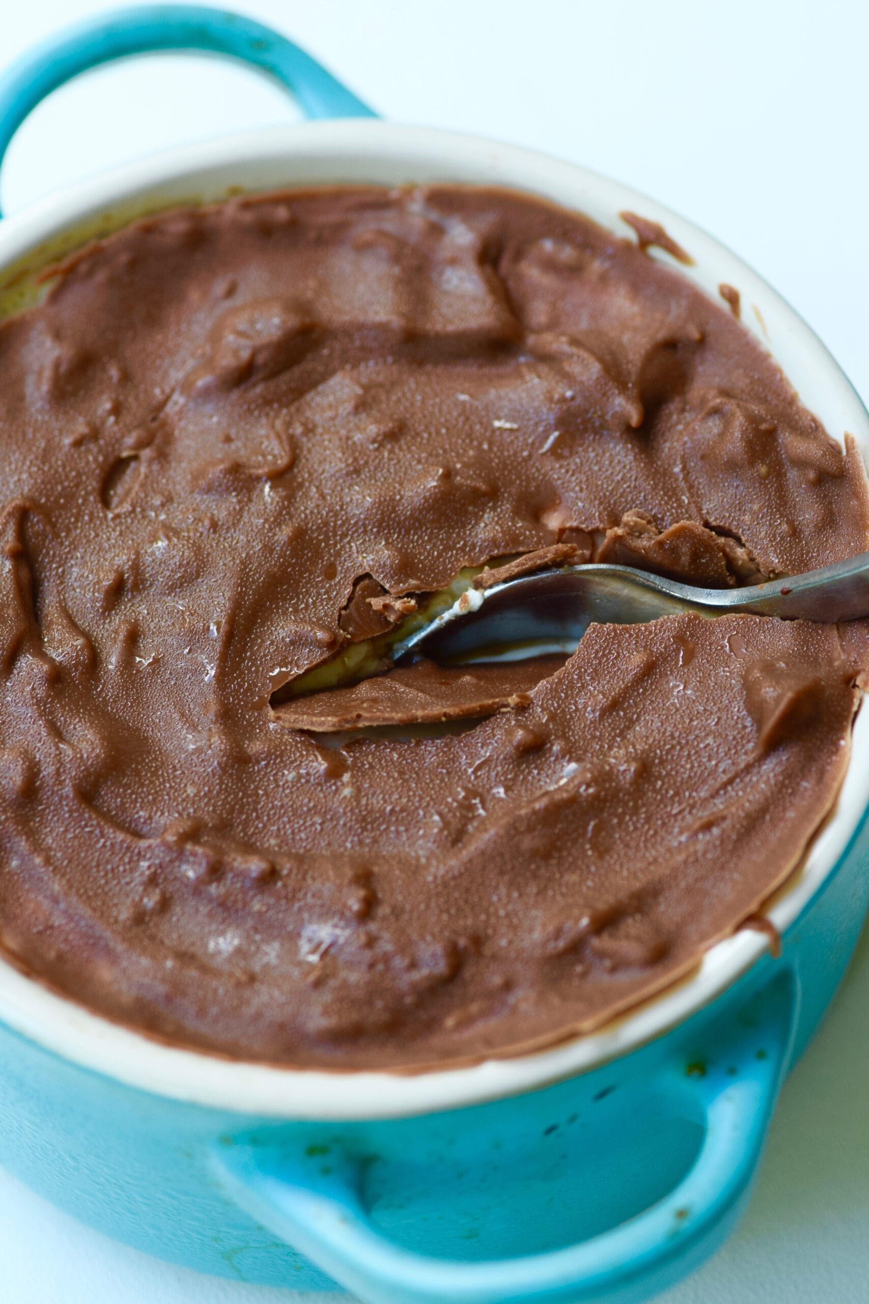 Spoon cracking chocolate layer in protein chocolate no bake cheesecake